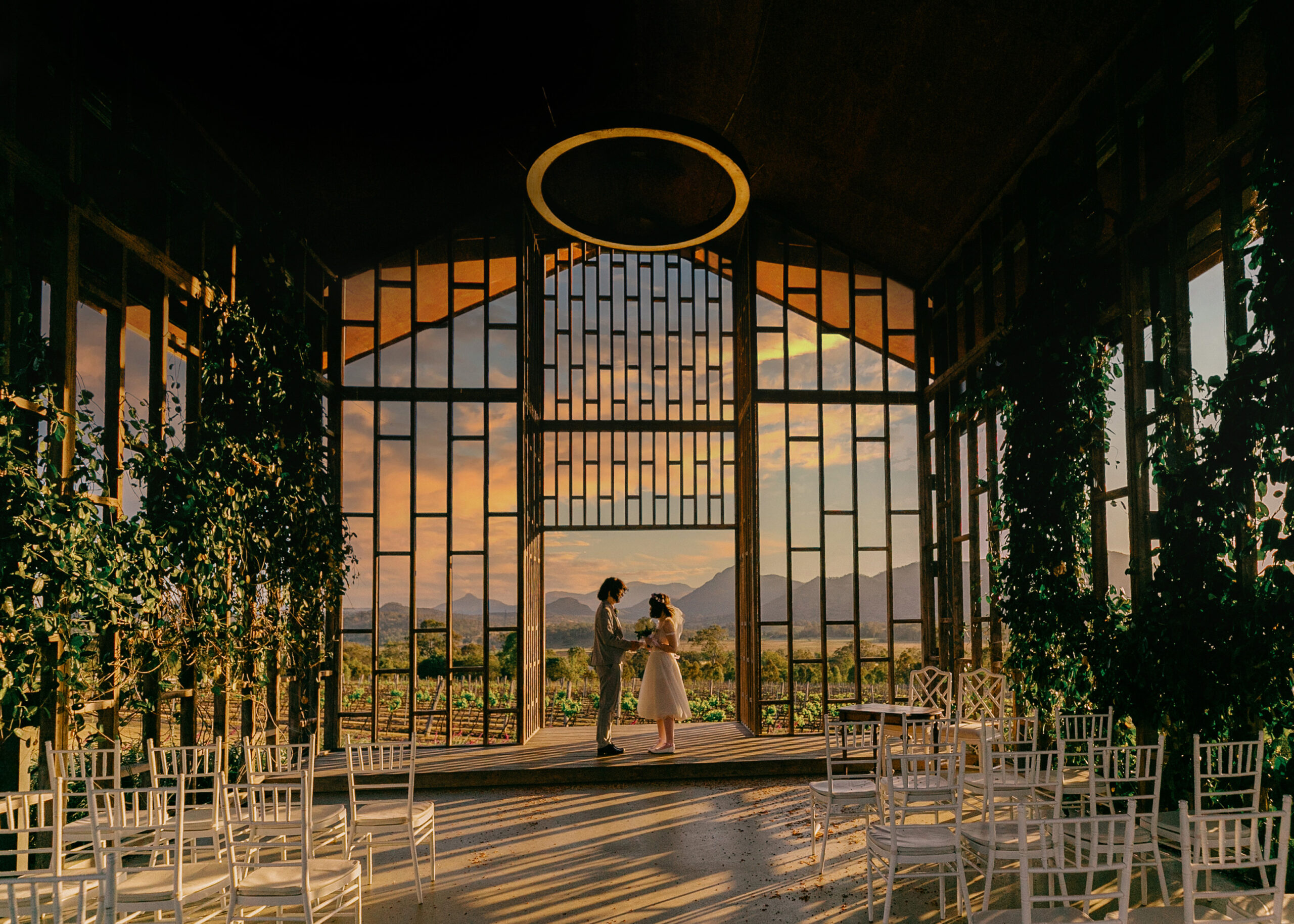 Bride and groom exchanging vows at sunset inside the glass chapel at Kooroomba Lavender Farm, with mountain views in the Scenic Rim, Queensland.