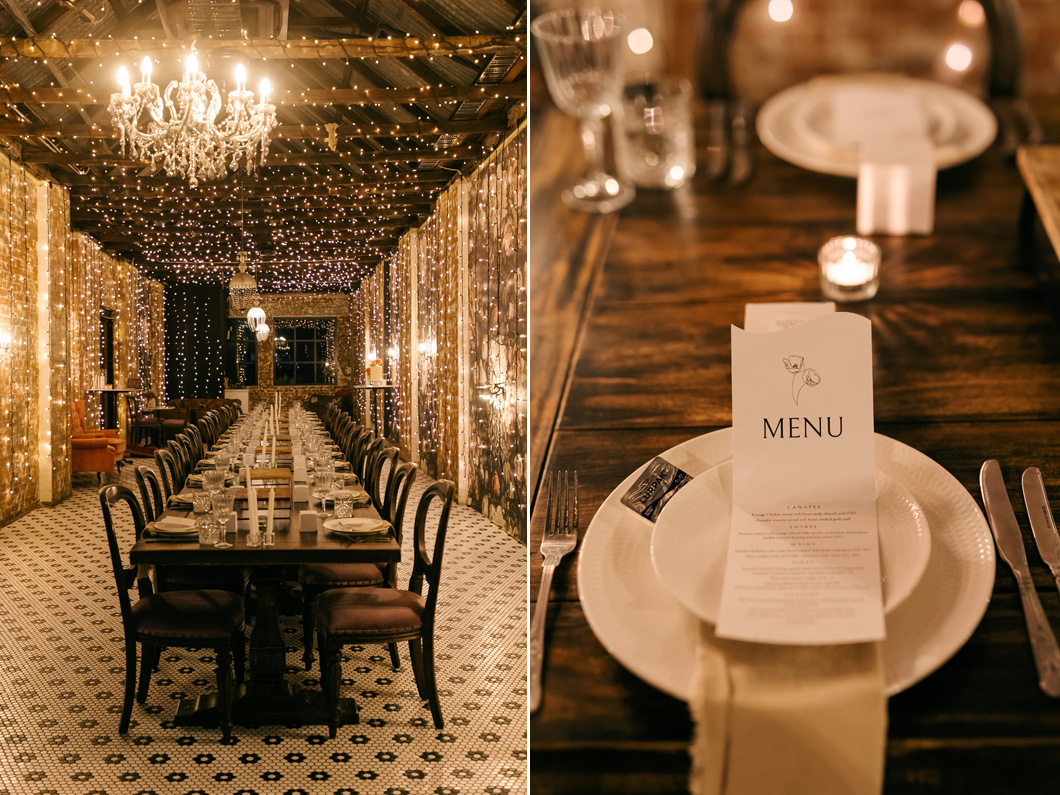 Wedding reception room with chandeliers and fairy lights, featuring long table settings with printed menus and soft candlelight.