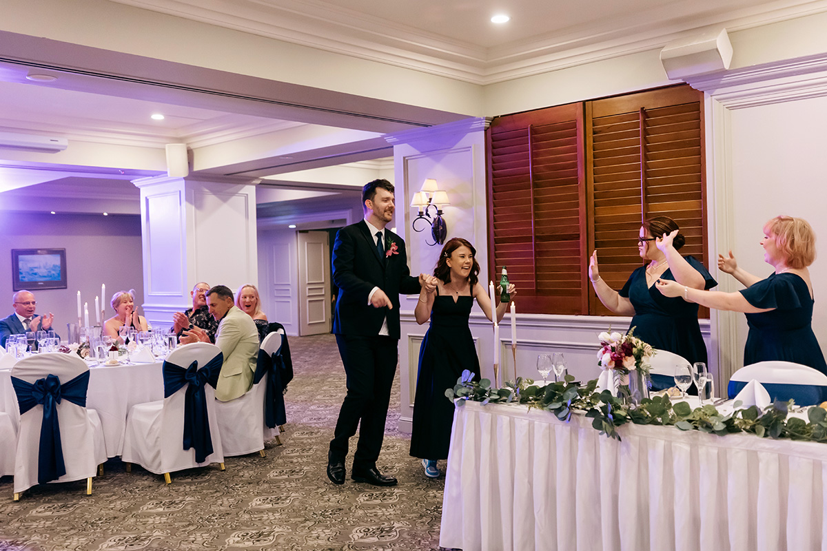 Bride and groom making a joyful entrance into the wedding reception at Stamford Plaza Brisbane, with guests clapping and cheering.